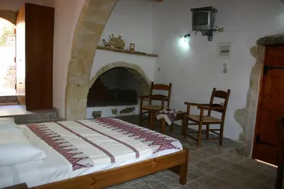 a bedroom with a bed and chairs and a fireplace at Vafes Traditional Stone Houses in Vafés