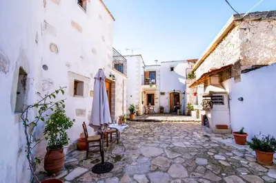 an outdoor courtyard with a umbrella and chairs and buildings at Vafes Traditional Stone Houses in Vafés