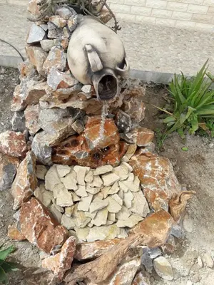 a water fountain in the middle of a pile of rocks at Kalyves Bay in Kalyves