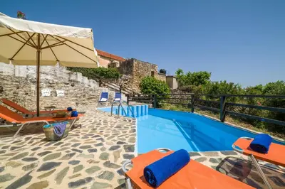 a swimming pool with chairs and an umbrella at Villa Zoi Tzitzifes in Tzitzifés