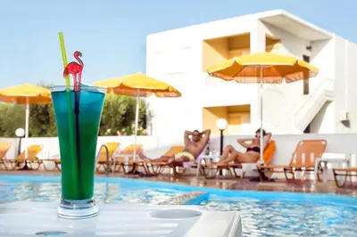 a drink sitting on a table next to a swimming pool at Elena Rooms & Apartments in Gerani Chanion