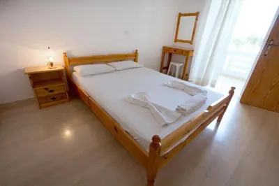a bedroom with a wooden bed with white sheets and a table at Elena Rooms & Apartments in Gerani Chanion