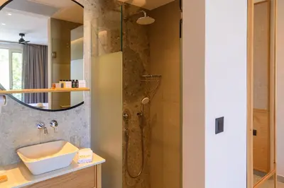 a bathroom with a shower with a sink and a mirror at Relax Hotel in Palaiochóra