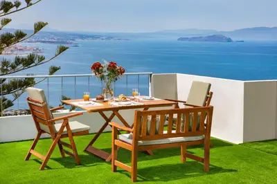 a table and chairs on a balcony with a view of the ocean at Sunset Home with sea view in Chania Town