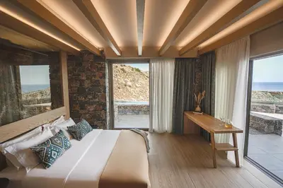a bedroom with a bed and a desk and windows at panorama new generation in Sfakiá