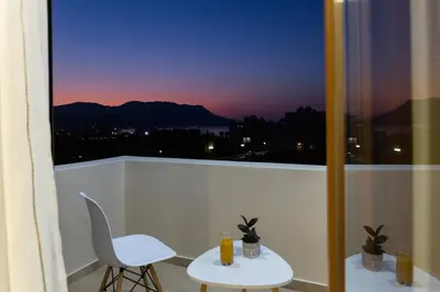 a balcony with a table and two chairs and a window at Gardenia Apartment in Kissamos