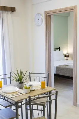 a room with a table and chairs and a bed at Gardenia Apartment in Kissamos