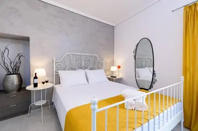 a bedroom with a white bed and a mirror at Family home w. yard in Beating Heart of Old Town in Chania Town
