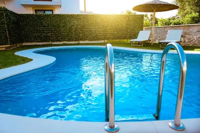 a swimming pool with blue water and an umbrella at Chania Oasis with heated pool in Chania Town