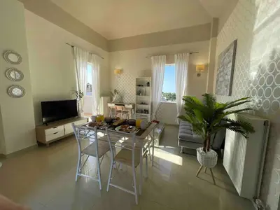 a living room with a table and chairs and a television at Artdeco Luxury Suites in Korakiaí