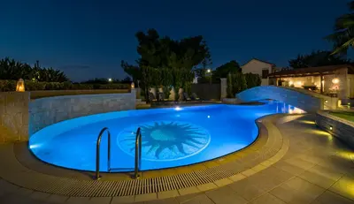 a swimming pool in a backyard at night at Artdeco Luxury Suites in Korakiaí