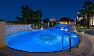a large blue swimming pool at night at Artdeco Luxury Suites in Korakiaí