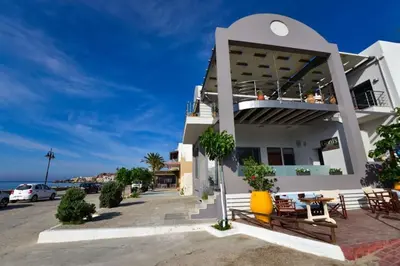 a white building with tables and chairs in a parking lot at Gonis Grand Luxury Suite in Palaiochóra