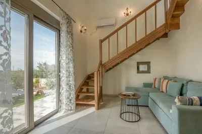 a living room with a blue couch and a staircase at Pink Sand Villas in Agios Padeleimon