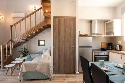 a kitchen and a living room with a staircase in a apartment at Pink Sand Villas in Agios Padeleimon
