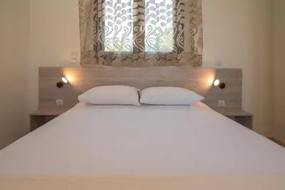 a bedroom with a large white bed with two pillows at Pink Sand Villas in Agios Padeleimon