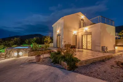 a villa with a swimming pool at night at Pink Sand Villas in Agios Padeleimon