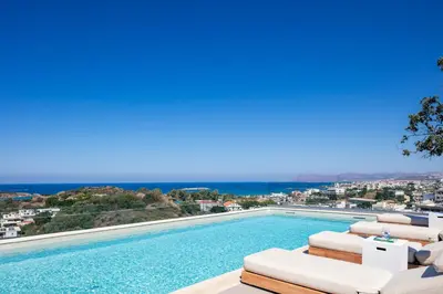 a swimming pool with lounge chairs and the ocean at Centro Golden View Villa in Chania Town