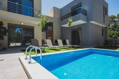 a villa with a swimming pool in front of a house at Park-view Lux Pool Villa, steps to the Beach in Aghii Apostoli