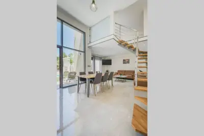 a dining room and living room with a spiral staircase at Park-view Lux Pool Villa, steps to the Beach in Aghii Apostoli