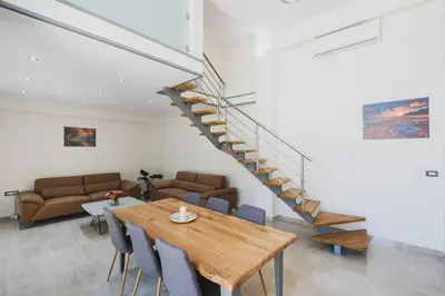 a living room with a wooden table and a staircase at Park-view Lux Pool Villa, steps to the Beach in Aghii Apostoli