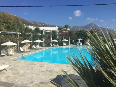 a large blue swimming pool with chairs and umbrellas at Hotel Plakures in Falasarna