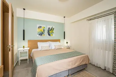 a bedroom with a bed and two tables and a window at Olga's Organic garden Home for a couple! with Wifi & AC in Chania Town