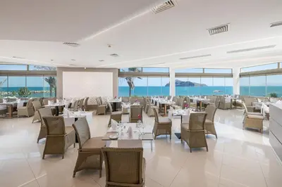 a restaurant with tables and chairs and the ocean at Porto Platanias - Casa Di Porto in Plataniás