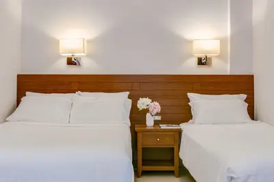 two beds in a hotel room with white sheets and flowers at Porto Platanias - Casa Di Porto in Plataniás