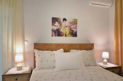 a bedroom with a bed with two lamps and a painting at Aristea's Apartment 2nd Floor in Chania Town