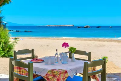 a table with a plate of food on the beach at Aristea's Apartment 2nd Floor in Chania Town