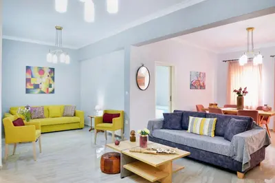 a living room with a blue couch and yellow chairs at Aristea's Apartment 2nd Floor in Chania Town