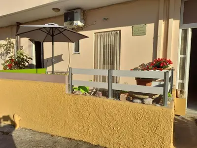 a bench sitting outside of a building with an umbrella at Kissamos Nice Apartment1 in Kissamos