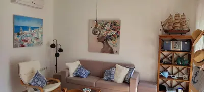 a living room with a couch and paintings on the wall at Kalyves Mili's house sea view in Plaka