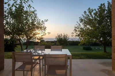 a table and chairs with the sunset in the background at Sunset Villas in Falasarna