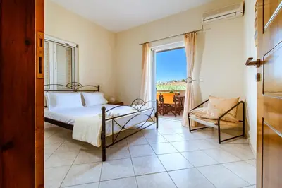 a bedroom with a bed and a window and a chair at Chania Grand Nature Apartment in Chania Town