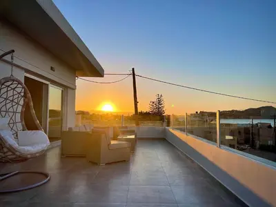 a balcony with chairs and a sunset on a building at Mira Sea View Residence in Chania Town