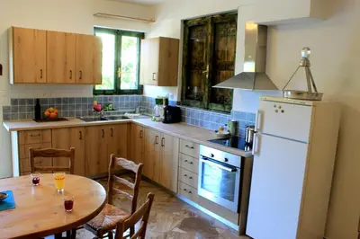 a kitchen with a wooden table and a white refrigerator at Village Villa Mimis Drapanias in Drapaniás