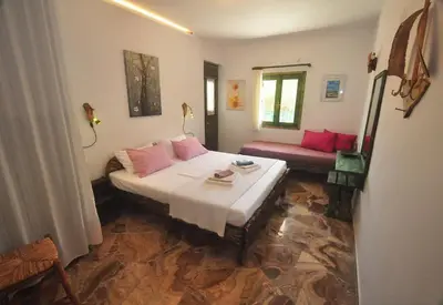 a bedroom with a bed with pink pillows at Village Villa Mimis Drapanias in Drapaniás