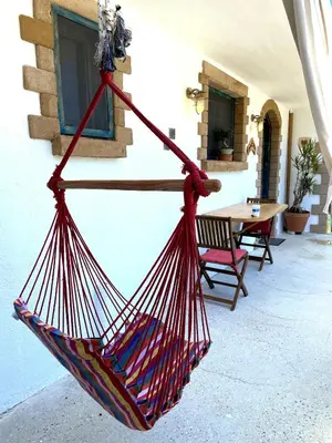 a red hammock hanging from the side of a building at Village Villa Mimis Drapanias in Drapaniás
