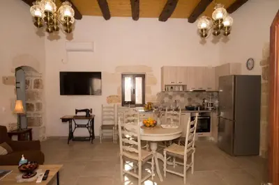a kitchen and living room with a table and a refrigerator at Iliopetra Villa in Beritianá