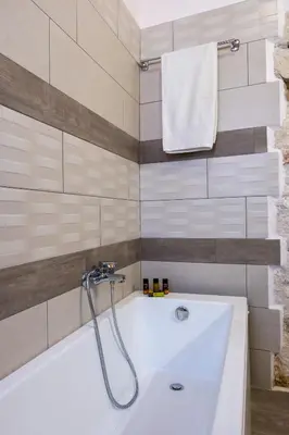 a bathroom with a bath tub with a shower at Traditional Cretan Villa George - Private Pool in Kambánion