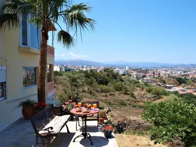 a table and chairs on a balcony with a palm tree at Emerald Apartment 2 Halepa in Chania Town
