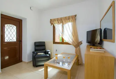 a living room with a table and a chair and a television at Lilium Stone Villa in Varípetron