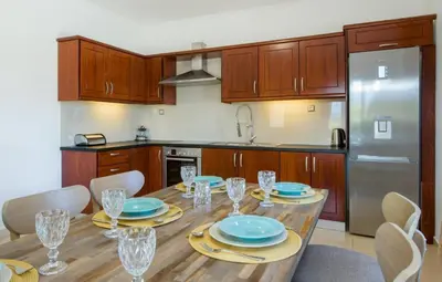 a kitchen with a wooden table with plates and wine glasses at Lilium Stone Villa in Varípetron