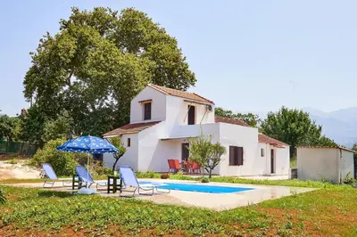 a house with a pool and two chairs and an umbrella at Platanos Stone House I With Shared Pool in Kalyves
