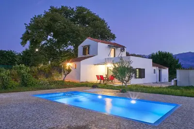 a villa with a swimming pool in front of a house at Platanos Stone House I With Shared Pool in Kalyves