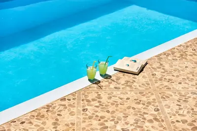 two glasses of juice next to a swimming pool at Platanos Stone House I With Shared Pool in Kalyves