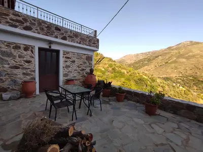 a patio with a table and chairs and mountains at Grandma Agatha & Virginia's stonehouse in Kefálion
