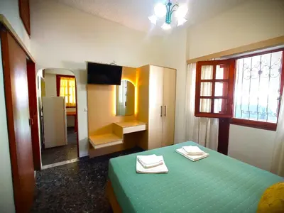 a bedroom with a green bed and a mirror at Tasos Seagull apartments in Chania Town